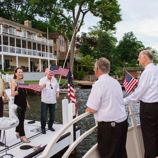 A group of seniors standing on a dock with handheld American flags